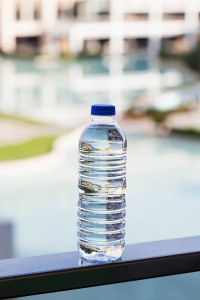 plastic transparent bottle of drinking mineral water on the background of an outdoor pool in a hotel in Turkey
