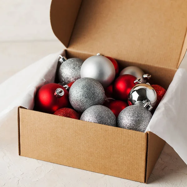 Juguetes de árbol de Navidad en una caja de artesanía. Las bolas son brillantes, rojas y plateadas . —  Fotos de Stock