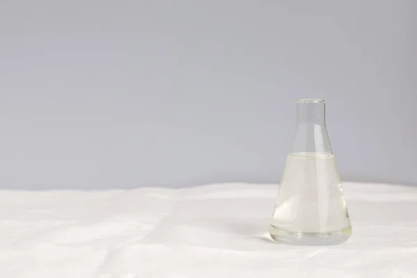 Glass transparent flask with water on a white tablecloth and with a blue background. Horizontal photo with a lot of space to enter text on the left side. Minimalism.