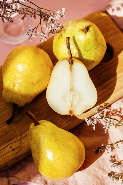 Still life of yellow pears on a pink background. Pears and whole pears in the cut.