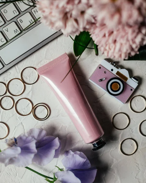 Pink tube for cream, cosmetics, flowers, gold rings.