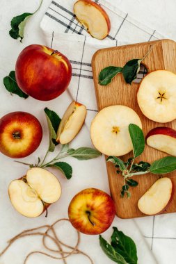 Kırmızı-sarı elmalar bir bütün, tahta bir tahta üzerinde kesilmiş ve arka planda yapraklar var..