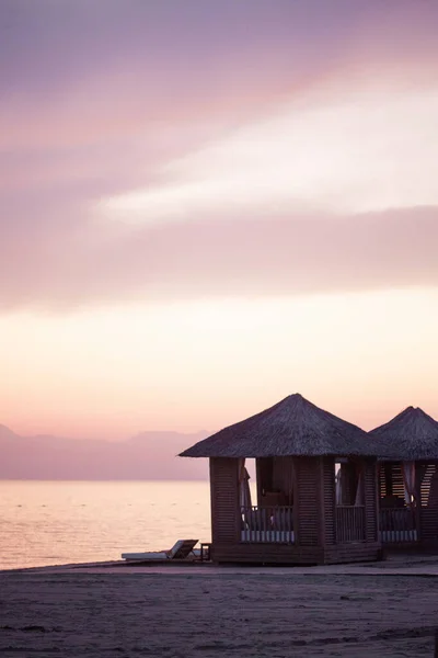 Bungalow aan een zandstrand tegen een roze zonsondergang in Turkije, Belek. Exclusieve vakantie aan zee. — Stockfoto