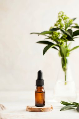 Cilt bakımı. Ahşap tezgahta nemlendirici serum, arka planda yeşil bitkili bir ampul..