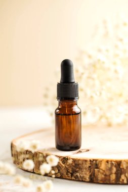 Yüzün ve vücudun derisi için beyaz küçük çiçeklerin arka planına yakın plan serum veya yağ. Cilde önem verir.