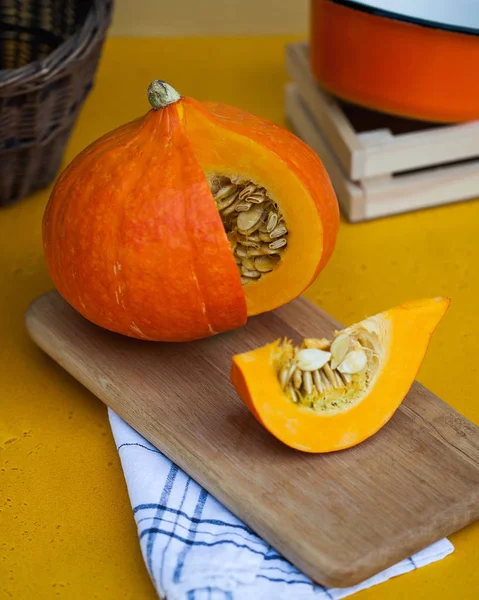 Redondea la calabaza madura en una sección sobre una tabla de madera, en el fondo una canasta de mimbre. menú para vegetarianos . —  Fotos de Stock