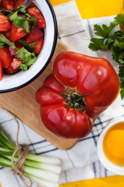 Tahta üzerinde dev, etli, kırmızı domates, yeşil salata ve domates tabağı. Sebze menüsü, vejetaryen menüsü..