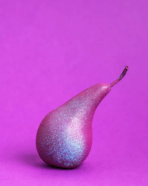 Bright purple pear close-up on a purple background. Vertical photo, there is space for text. Creativ concept.