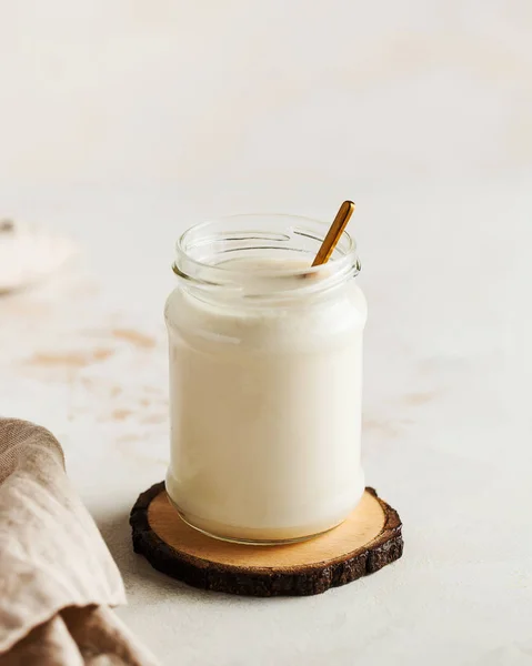 Healthy breakfast. Thermostatic fermented milk product, natural yogurt in a glass jar on a tree cut. — Stock fotografie