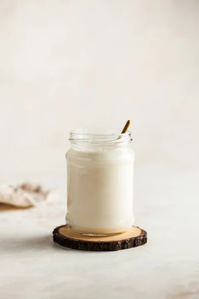 Healthy breakfast. Thermostatic fermented milk product, natural yogurt in a glass jar on a tree cut. — Stock fotografie