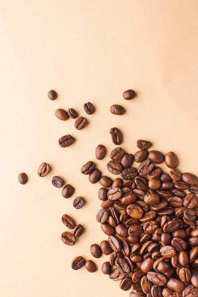 Granos de café en la esquina inferior sobre un fondo marrón. Foto vertical con espacio para texto. Para cafés y cafeterías . — Foto de Stock