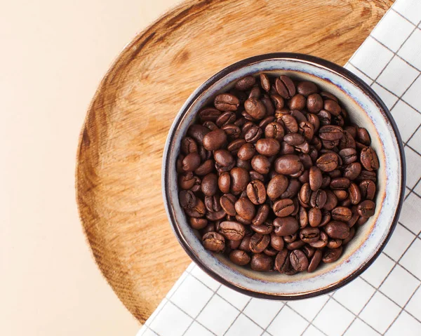 Granos de café Arabica en un tazón de cerámica en una bandeja de madera sobre un fondo marrón. Foto horizontal con espacio para texto . — Foto de Stock