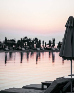  Gün batımında güneşli yatakları olan terk edilmiş bir açık havuz. Turizm kavramı, salgın sırasında kriz.