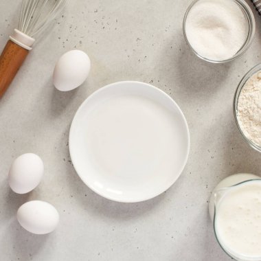  Unla pişirmek için gereken malzemeler ve boş beyaz tabakla çırpmak için. Minimalizm tarzında yiyecek kavramı.
