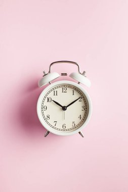  Fotokopi alanı olan pembe arka planda beyaz retro alarm saati. Zaman planlama ya da çalışma saatleri kavramı. Minimalizm. Zaman kavramı çalışıyor..