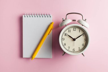  Flatlay Notebook, pembe arka planda kalem ve çalar saat. Yapılacaklar listesi için boş kart, grafik, düzen, metin, tasarım. Zaman kavramı, son tarih veya hatırlatma.