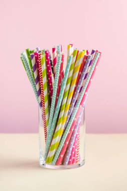 Renkli arka planda bir bardakta içmek için renkli kağıt tüpler. Parti, kutlama, doğum günü konsepti. Boşluğu kopyala