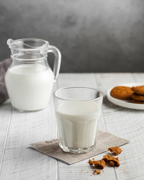 Glass of milk, jug of milk, cookies on a gray background. The concept of milk, the use of dairy products, agricultural products. MinimalismCopy space. Vertical food photo.
