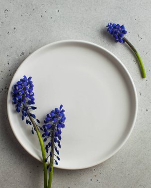  Flatlay. Ürünlerinizi eklemek ya da mor çiçekli metinler göndermek için boş beyaz tabak. Sanat konsepti, minimalizm, güzellik.