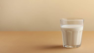  Kahverengi arka planda yakın plan çekilmiş bir bardak süt. Çiftlik süt ürünleri konsepti, süt kullanımı. Uzayı kopyala Yatay yemek fotoğrafı..