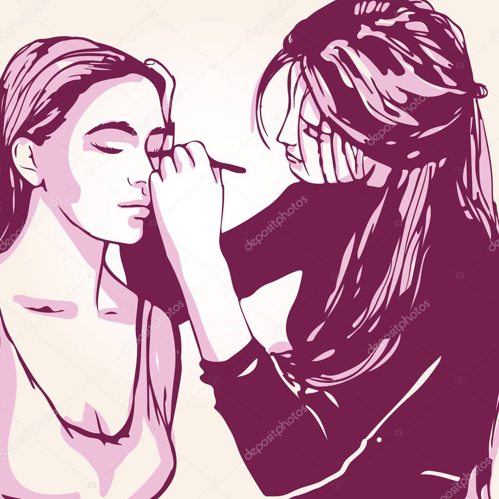 Woman visagist makeup artist paints on the face of his client.