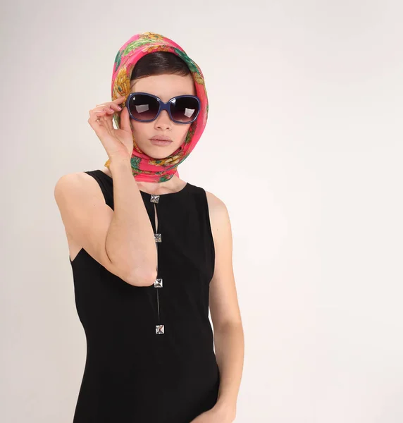 Mooie vrouw in retro stijl met hoofddoek en zonnebril op lichte achtergrond — Stockfoto