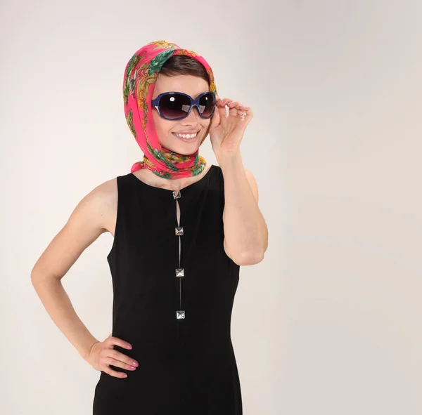 Bela mulher em estilo retro com lenço de cabeça e óculos de sol no fundo de luz — Fotografia de Stock