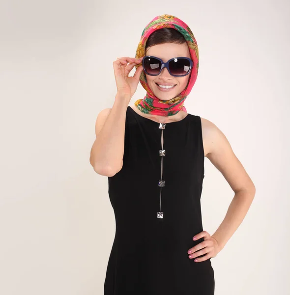 Mooie vrouw in retro stijl met hoofddoek en zonnebril op lichte achtergrond — Stockfoto