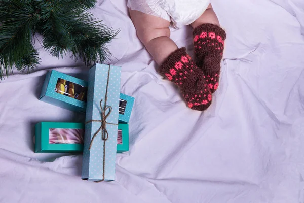 Child in warm knitted socks, christmas tree, gifts of cookies sweets — Stock Photo, Image