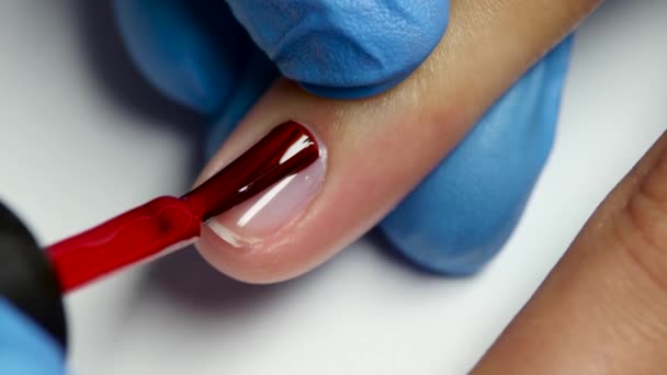 Master täcker naglar av klienten genom en röd lack. Närbild — Stockvideo