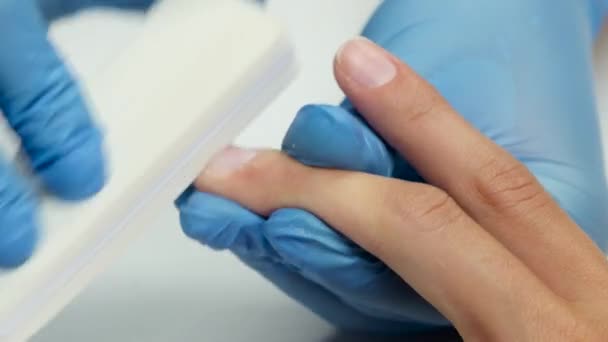 Manicura maneja las uñas del cliente por lima de uñas. De cerca. — Vídeo de stock