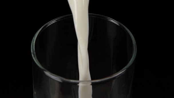 Verser le lait dans le verre. Noir. Au ralenti. Gros plan 