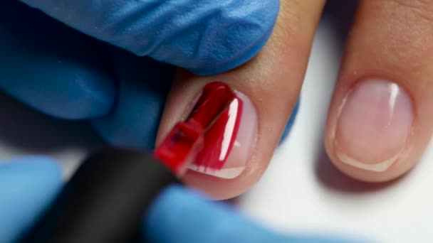 Manicurist does nail by red varnish. Close up — Stock Video