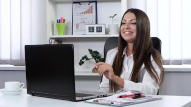 Office bir dizüstü bilgisayar ve bir web kamerası üzerinde konuşurken önünde oturan iş kadını mutlu ve gülümseyerek