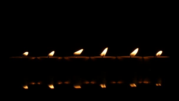 Seis velas em um fundo refletor preto. Fechar — Vídeo de Stock