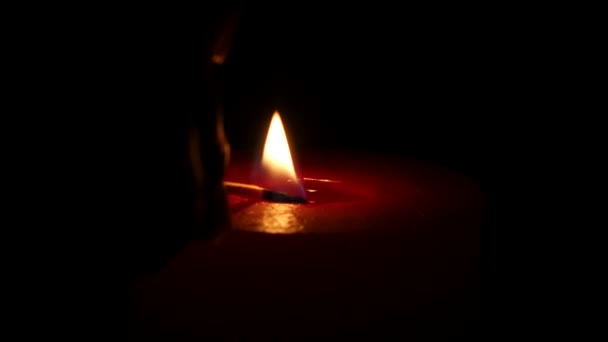 Burning red candle, isolated on the black background. Close up — Stock Video