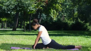 Parkta bir yoga mat üzerinde streç bir egzersiz yaparak çalışan kadın