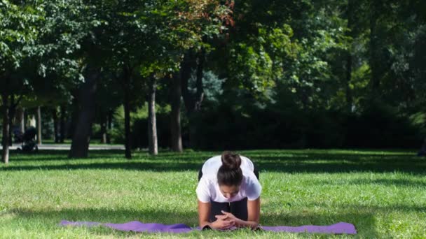 Fit girl faire du yoga dans le parc par une journée ensoleillée 