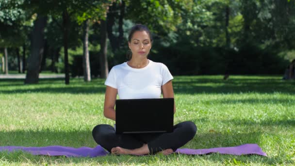 Yoga de chicas en el parque trabajando en un portátil — Vídeos de Stock