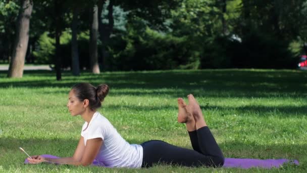 Girl makes a selfie doing yoga. Sunny day in park — Αρχείο Βίντεο