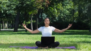 Lotus poz oturan laptop ile çalışan kadın. Yoga