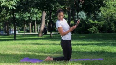 Kız bir mindere oturmuş ve selfie yoga konumda akıllı telefon ile yapıyor
