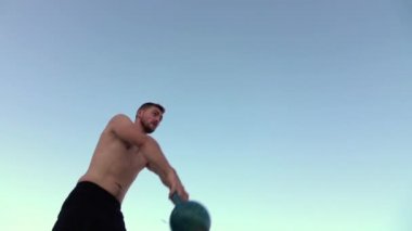 Adam ağır çekimde başının üzerine halter kaldırıyor. Ağır çekim