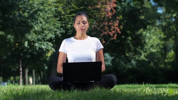 Vrouwelijke student zitten in het park met behulp van laptop. — Stockvideo