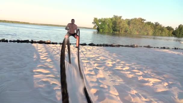 Gente comprometida con la cuerda en la orilla arenosa. Movimiento lento — Vídeo de stock