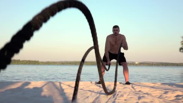 Man bedriver utbildning med repen på den sandiga stranden. Slow motion — Stockvideo