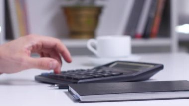 Hesap makinesinde sayma ve not defterine yazma planı olan adam. Yakın çekim