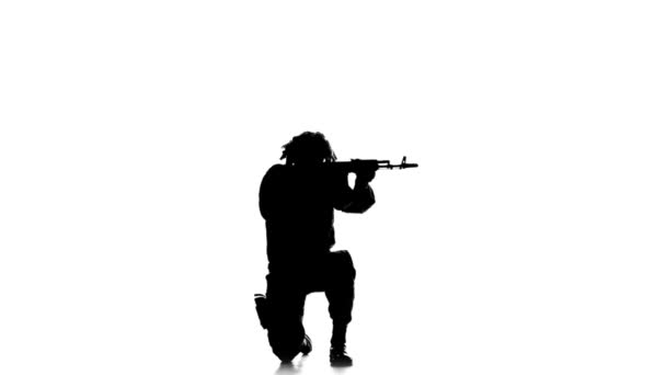 Soldier stands on one knee and aiming a gun. Silhouette — Stock video