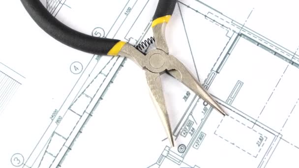 Gray and yellow round-nose pliers on building plan, scheme, rotation, close up — Stock video