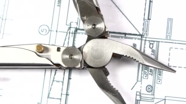 Metal round-nose pliers on building plan, scheme, rotation, close up — Stockvideo